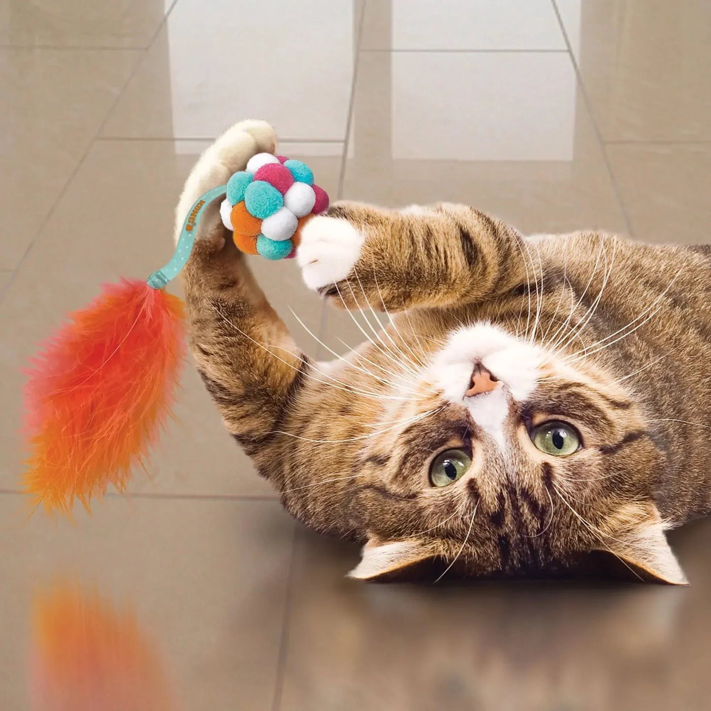 A colorful fluffy cat toy with a pom-pom ball and feather tail perfect for tack shop or equestrian cat play