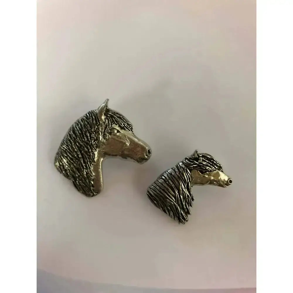 Two silver-tone metallic animal head stock pins with textured manes perfect for competition accessories