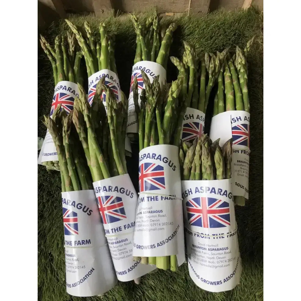 Bundles of fresh green asparagus wrapped in white paper with union jack labels from the farm for farm fresh produce