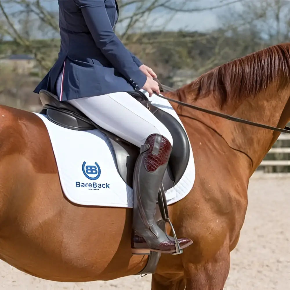 White bareback saddle pad with blue logo and black trim paired with bareback footwear milan long dress riding boots brown