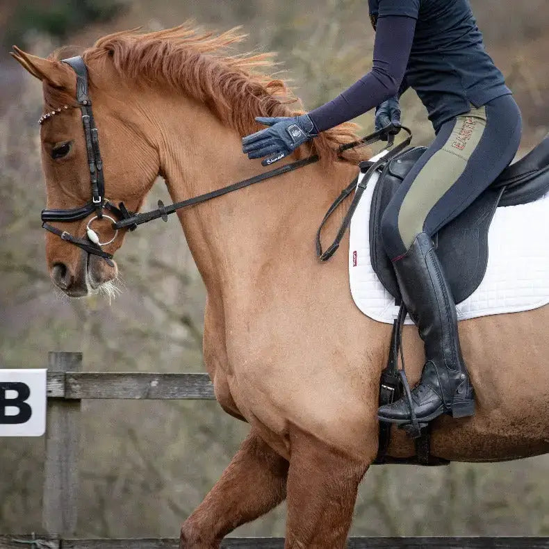A chestnut horse with flowing mane ridden by an equestrian wearing black leather bareback footwear kentucky half chaps