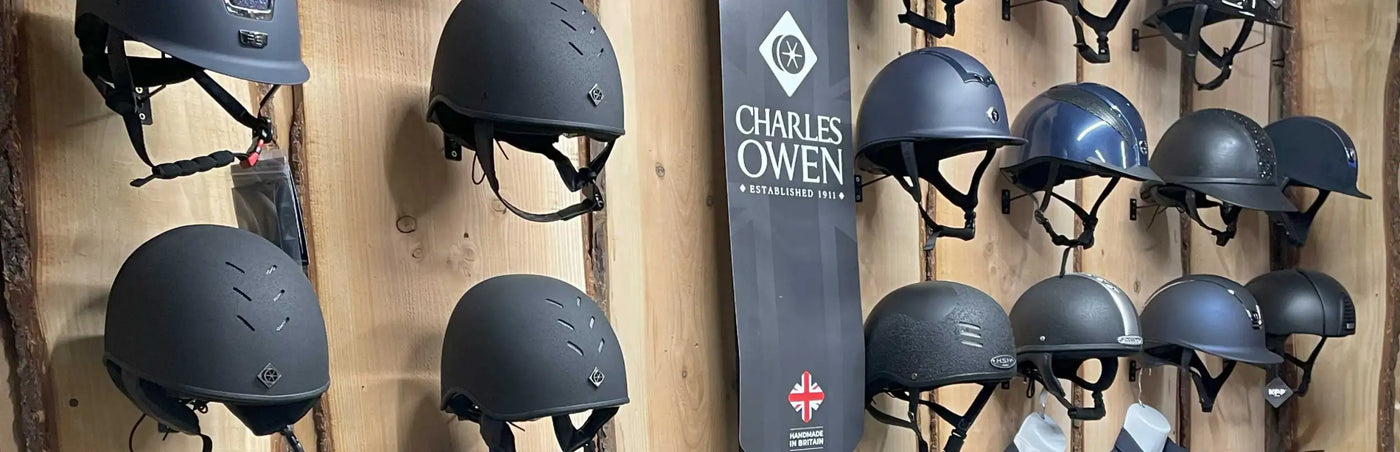 Black charles owen equestrian helmet with ventilation slots and adjustable straps.