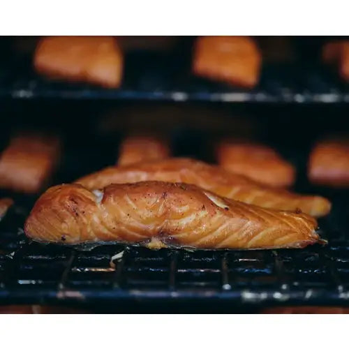 Grilled blakewell smokehouse superior devon hot smoked salmon fillet with golden-brown char on black grill grate