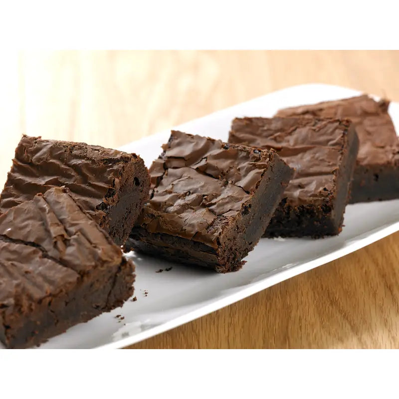 Rich fudgy chocolate brownie with a glossy cracked top on a white plate from brownie gf handmade cake co