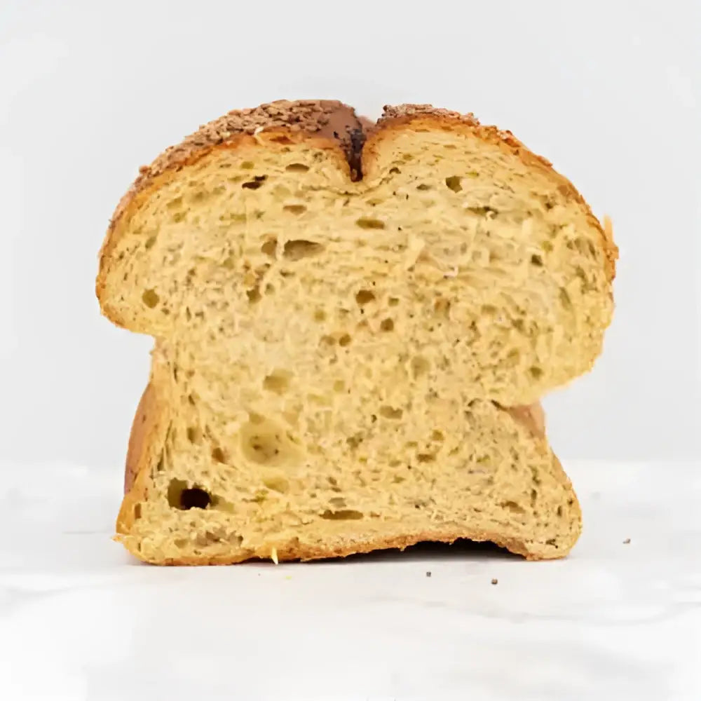 A slice of golden brown corn bread farmhouse loaf with airy interior and crust sprinkled with seeds