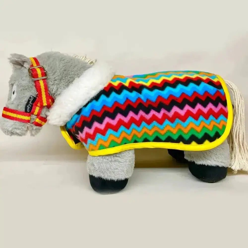 A plush gray horse wearing a crafty ponies fleece neck show rug with a colorful zigzag fleece blanket and yellow trim