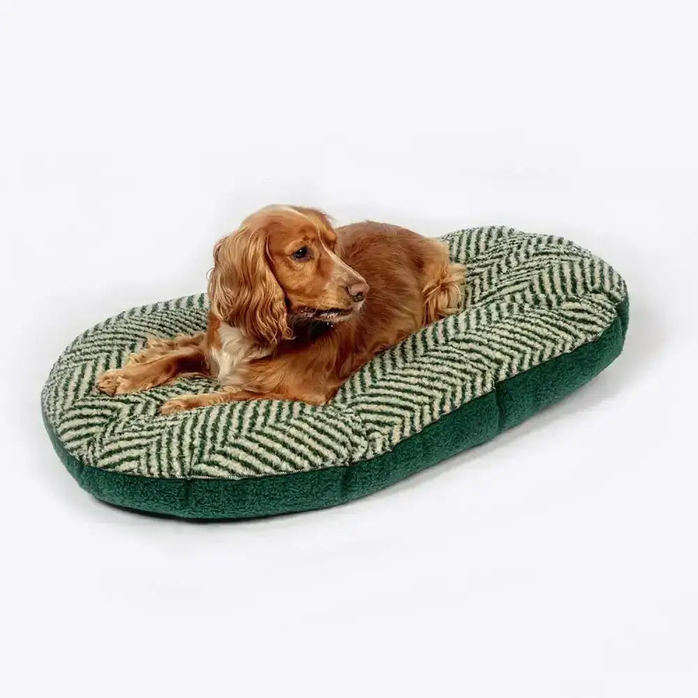 A cozy oval dog bed with danish design green herringbone fleece quilted top and plush dark green sides
