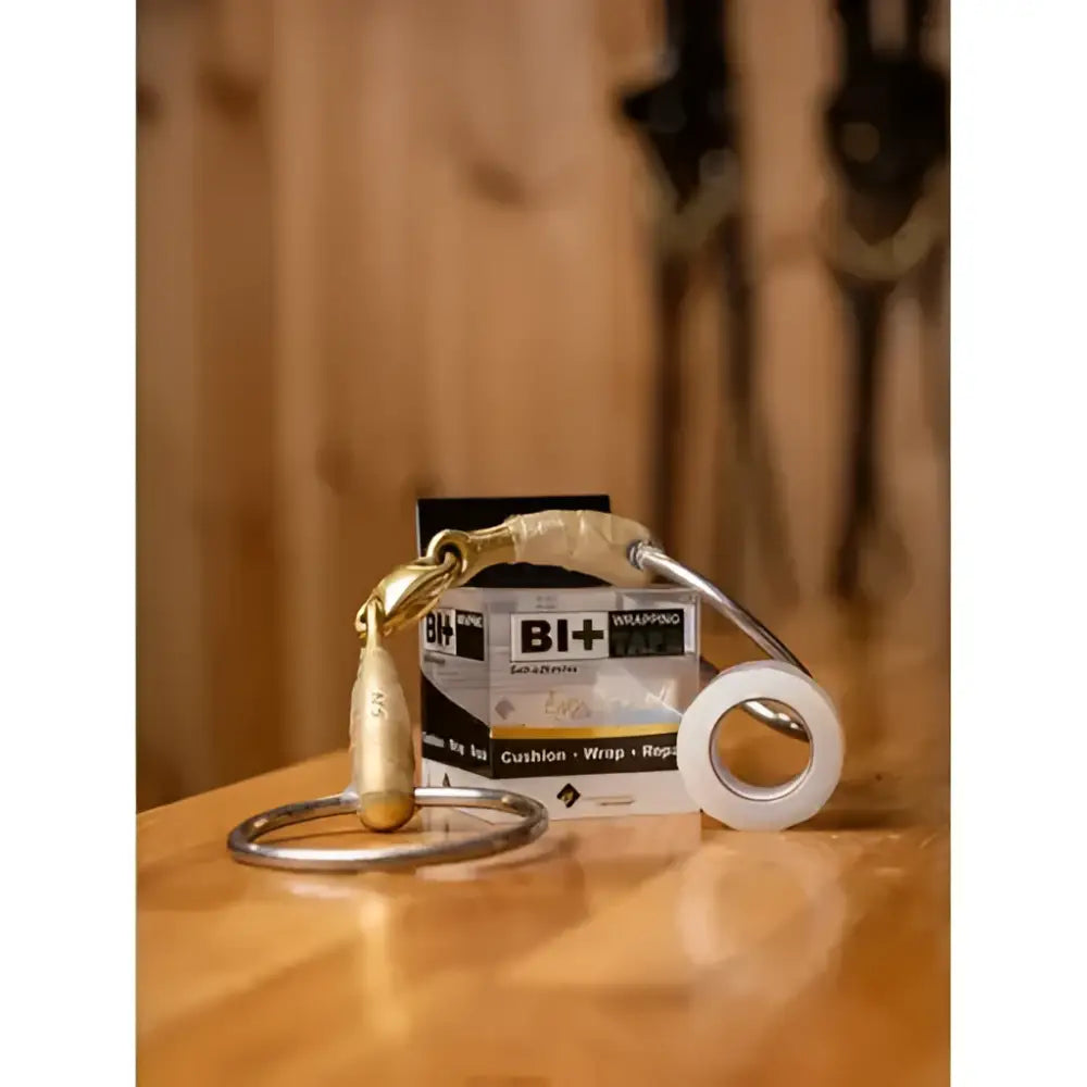 Gold metal horse bit with polished finish next to white roll of ehi bit wrapping tape for secure bit wrapping