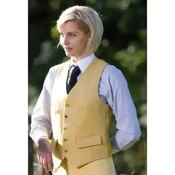 A mustard-yellow equetech classic waistcoat with gold buttons and flap pocket worn over a light blue striped shirt for casual wear