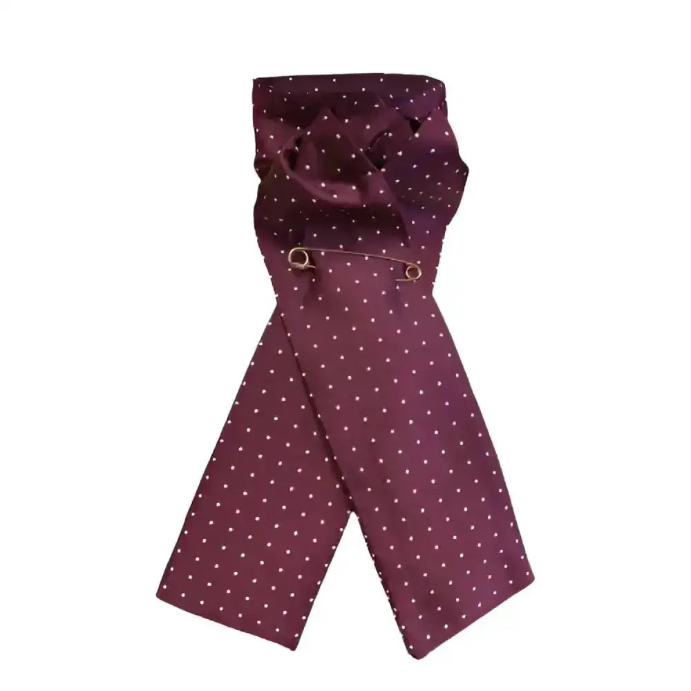 A maroon equetech pin spot riding stock made from jacquard fabric with white polka dots secured by a gold pin