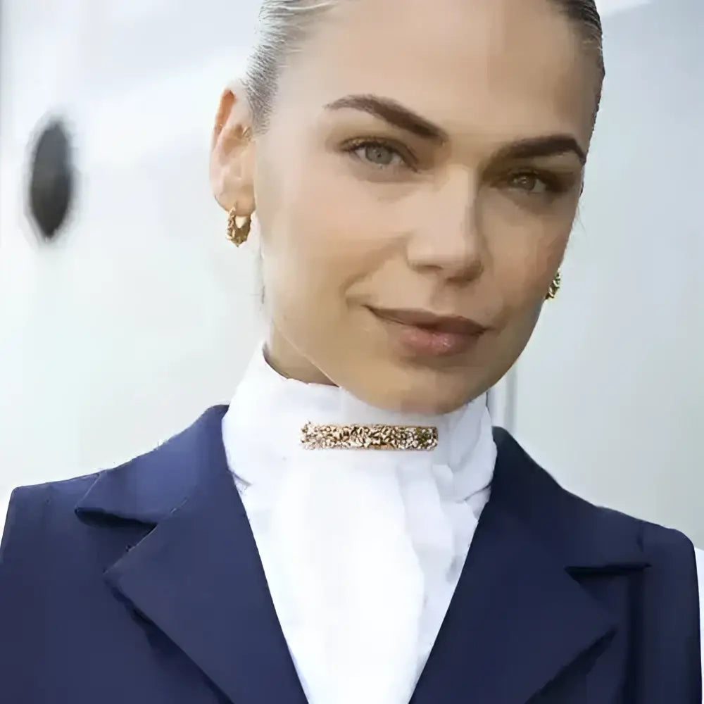 Gold-toned sparkling equetech ready-tied stock rose gold crystal brooch pinned at the collar of a white shirt
