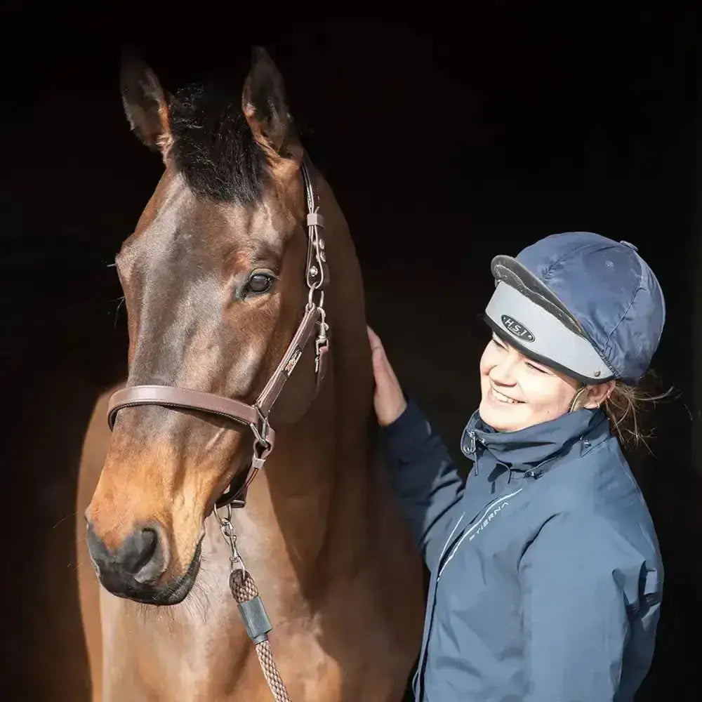 A dark brown horse wearing a tan leather equilibrium stella field safe head collar with a sleek black mane