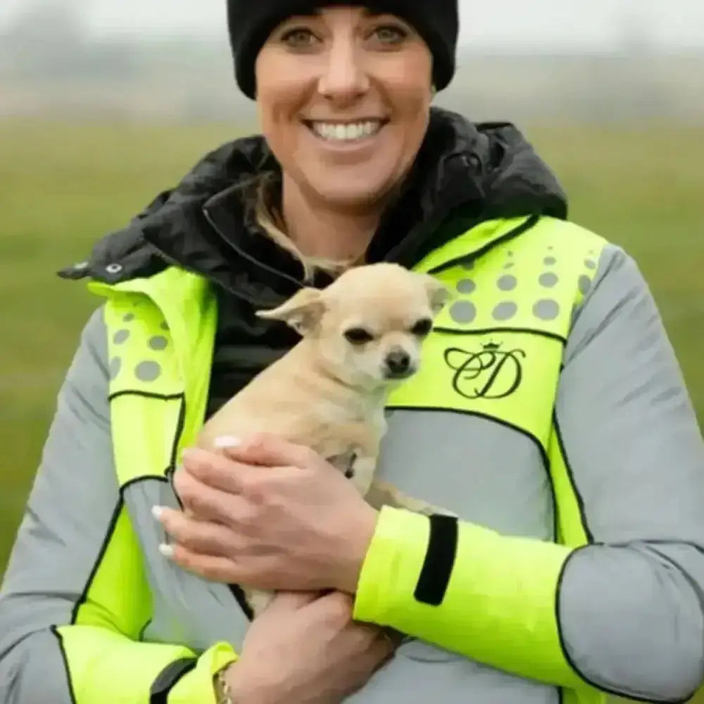 A small light tan chihuahua puppy with perked ears sitting near an equisafety mercury lightweight reflective riding coat