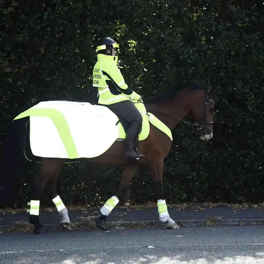 A rider on a dark brown horse wearing a neon yellow hi viz vest with advanced reflective material for safety