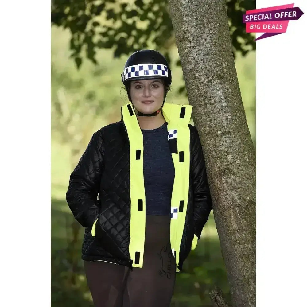 A woman wearing a black helmet and yellow equisafety polite winter inverno equestrian jacket childs for safety
