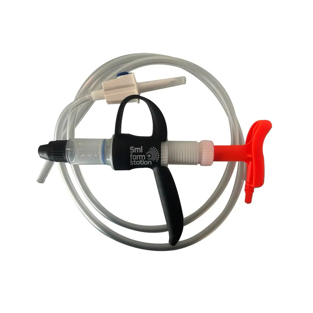Red and black plastic semi disposable vaccinator with clear barrel and coiled tubing labeled 5ml for farm station semi use