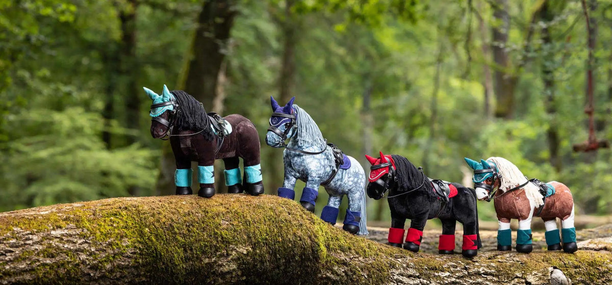 Four whimsical, stylized toy horses with colorful accents and unique markings stand in a row on a mossy log.