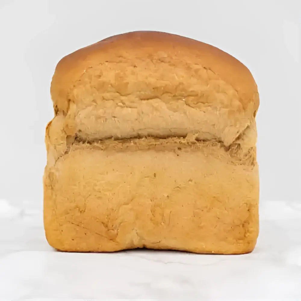 Golden brown german rye loaf dusted with flour showing a soft cracked crust and dense interior of round white bread