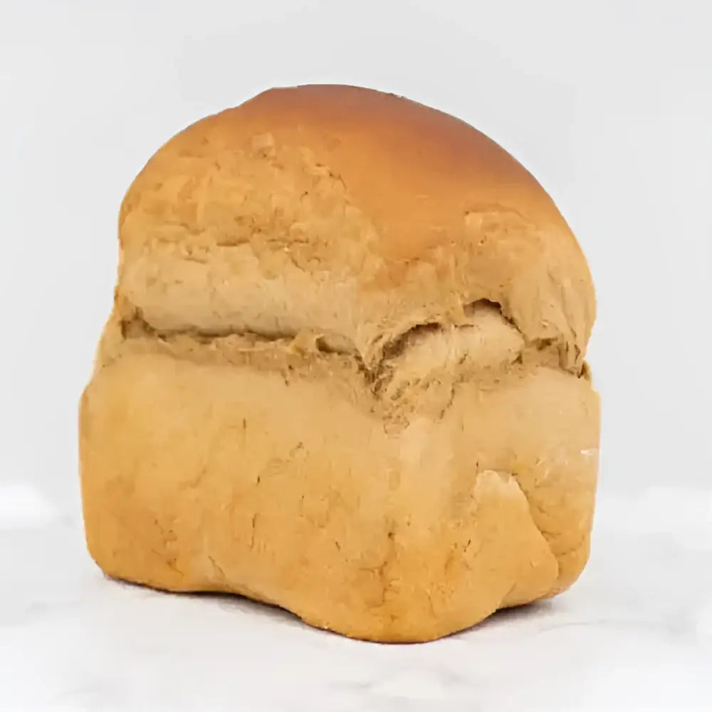 Golden brown german rye loaf dusted with flour featuring a soft texture and slightly cracked crust