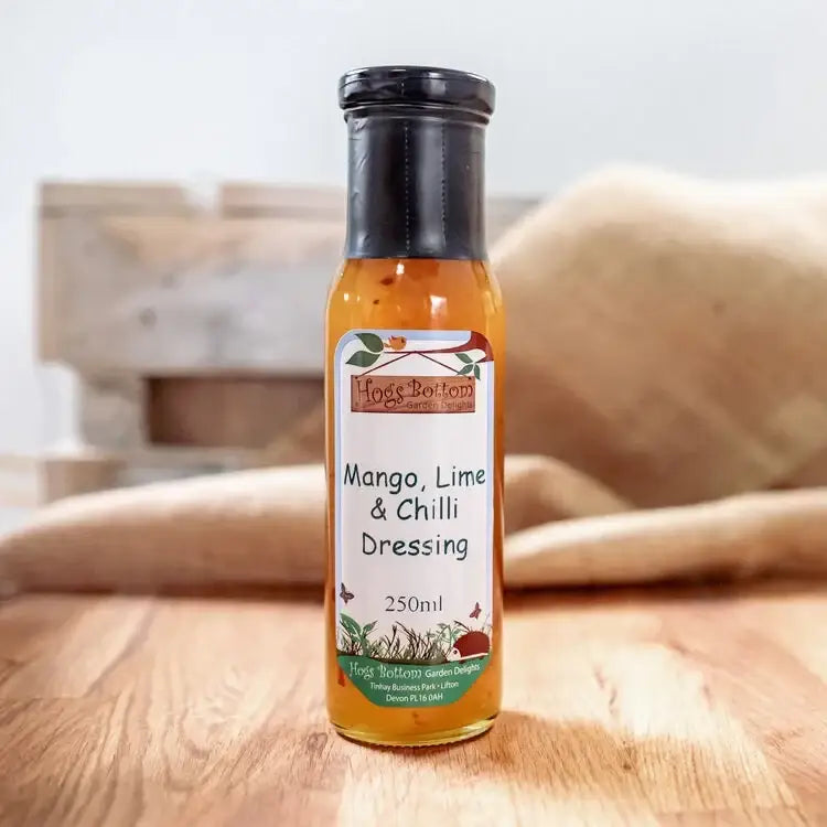 A clear glass bottle with black cap filled with orange hogs bottom mango lime and chilli dressing 250ml ideal for smokin jones bbq