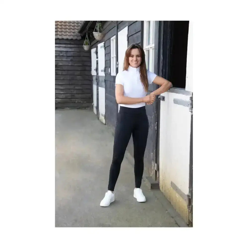 Woman wearing white short sleeved turtleneck top and black hy equestrian children’s melton riding tights
