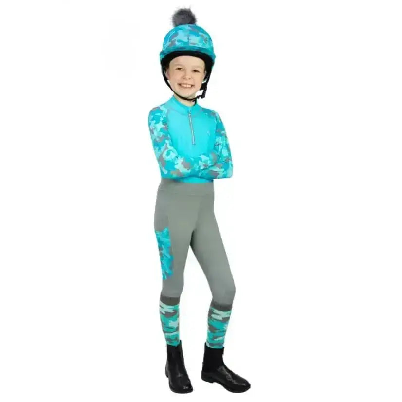 A child wearing a hy equestrian dynaforce base layer with turquoise gray camouflage print arms and matching helmet