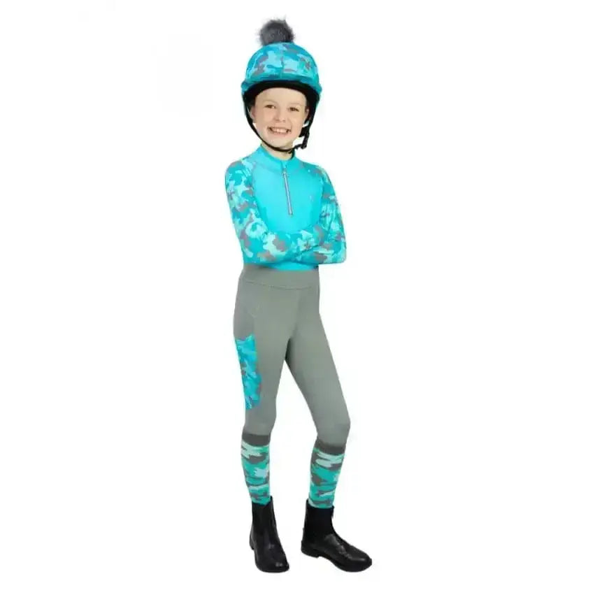 A child wearing turquoise and gray camouflage hy equestrian dynaforce riding tights with matching helmet and black pom-pom