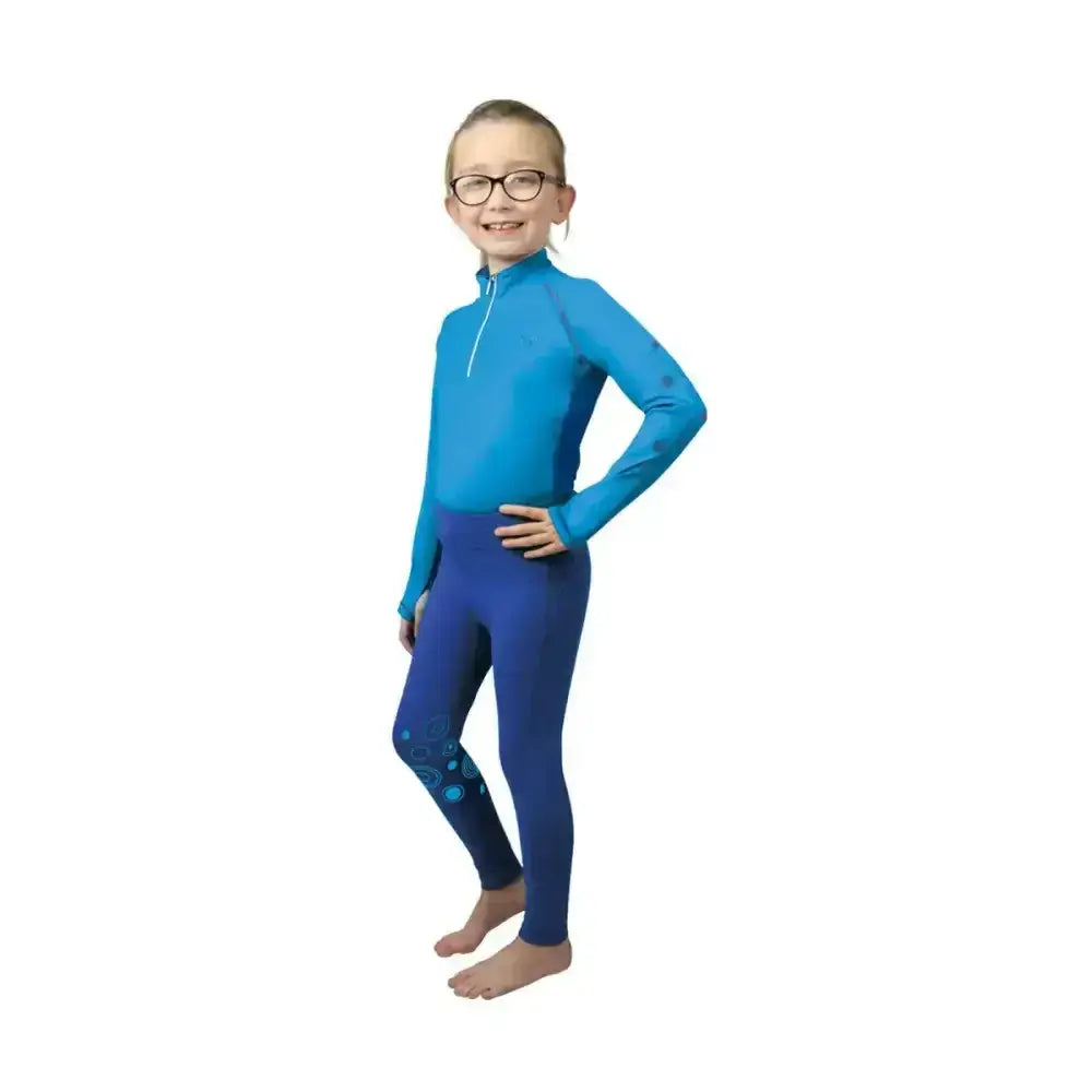 A child wearing a blue equestrian dynamizs ecliptic baselayer with patterned leggings perfect for active equestrian activities