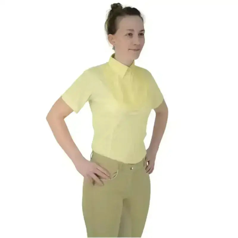 A woman wearing a pale yellow equestrian ladies tilbury short sleeved tie shirt with beige pants