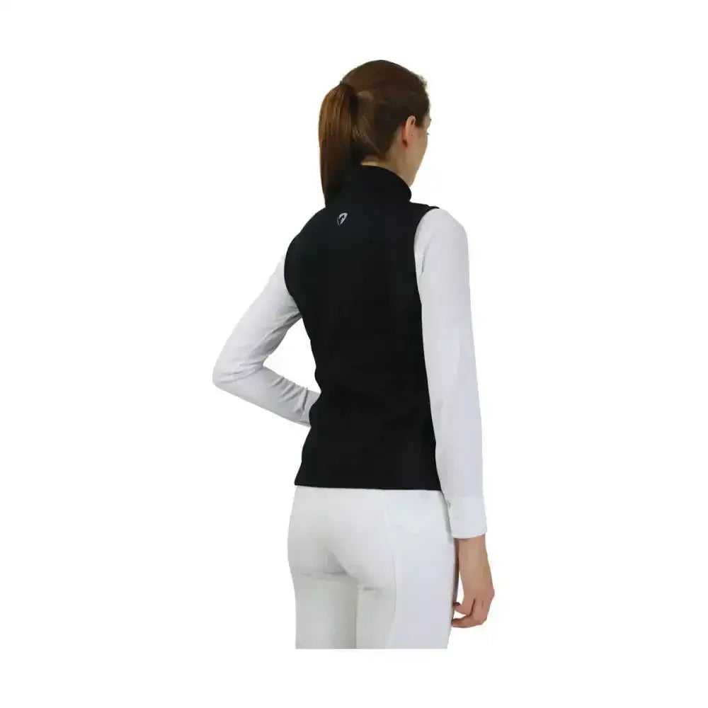 Back view of black hy equestrian synergy flex gilet with small logo worn over white long-sleeved shirt 4-way stretch soft