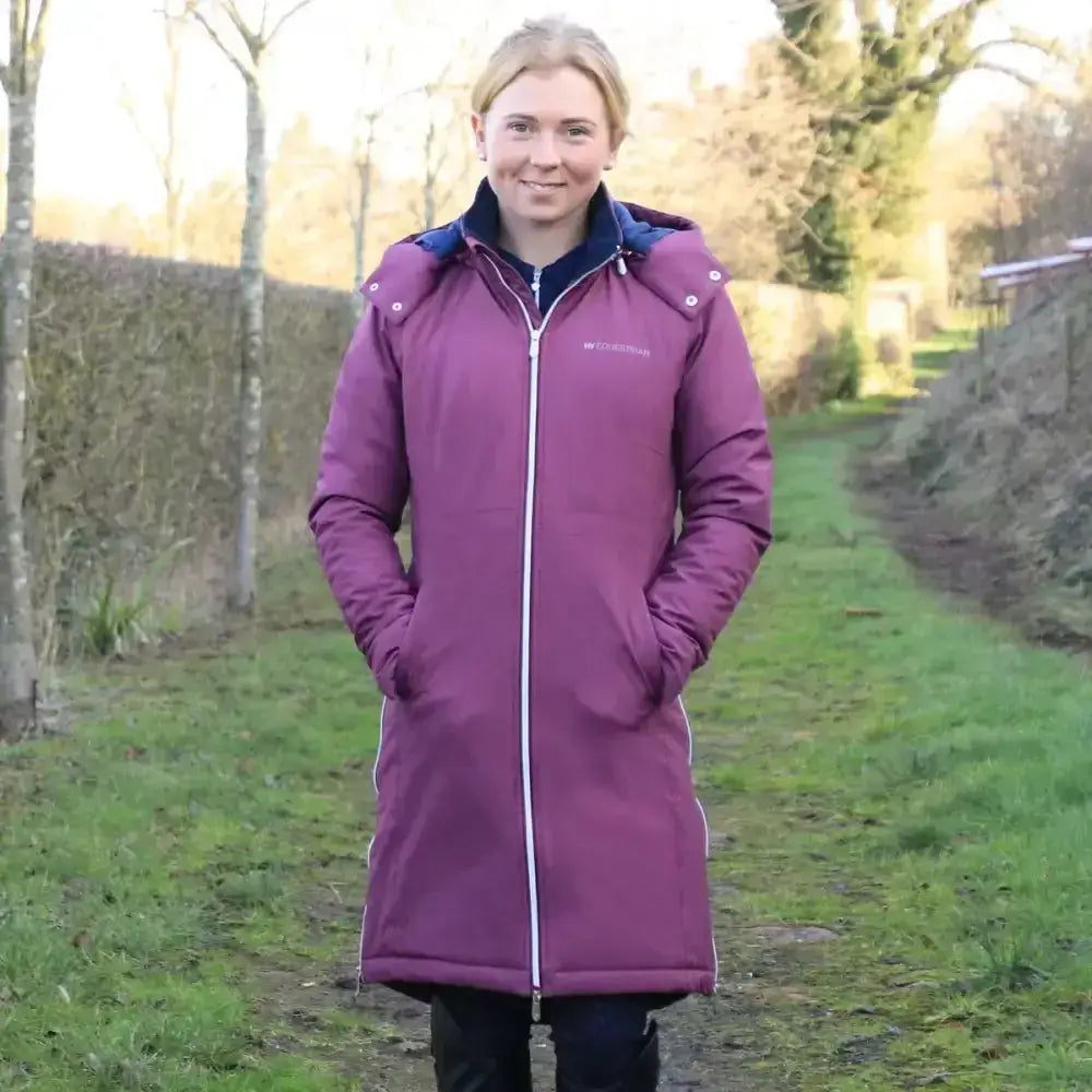 A maroon hy equestrian synergy guard fitted long waterproof puffer coat with navy blue hood and white zipper trim