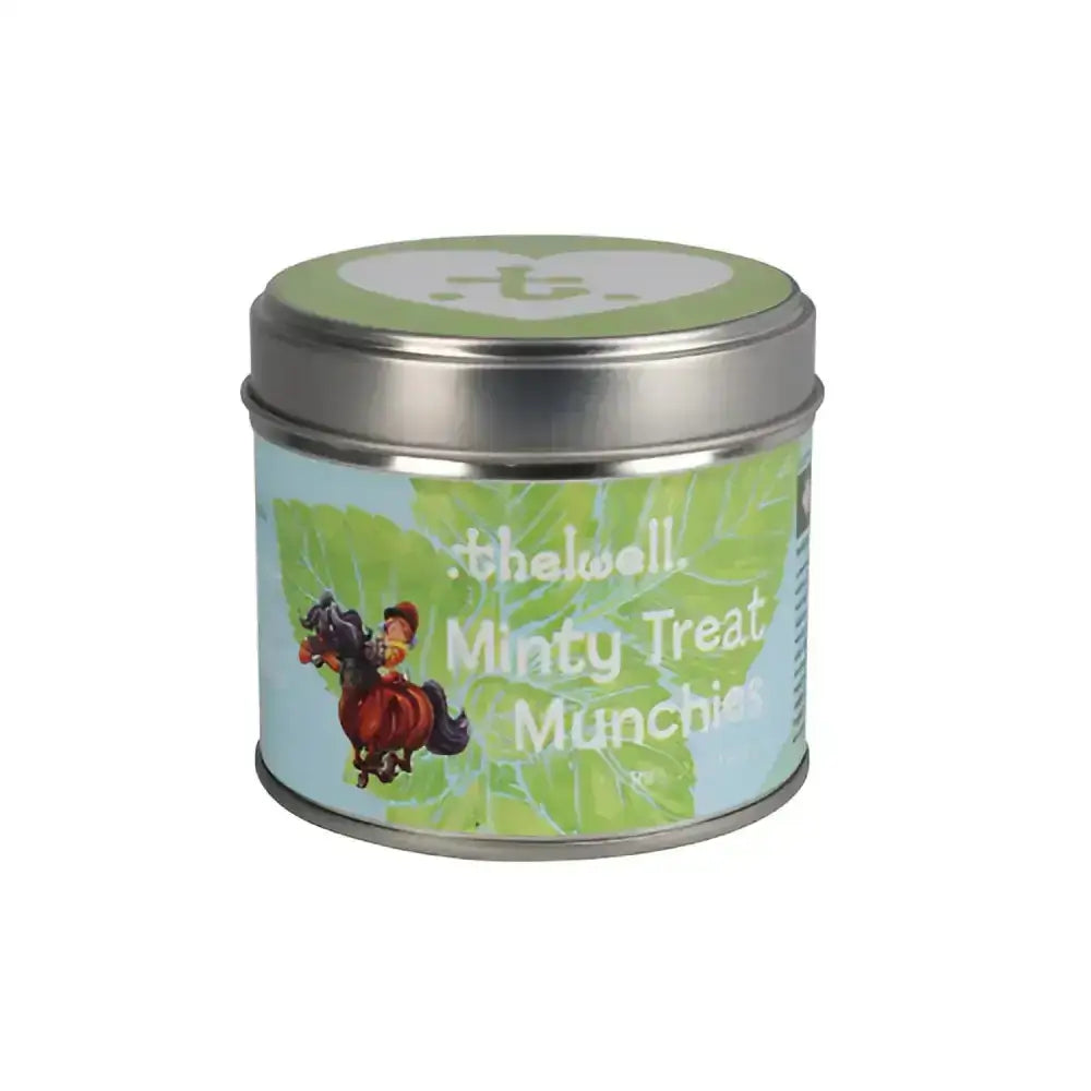 A cylindrical metal tin with a silver lid and blue-green label from the equestrian thelwell collection candle by the well