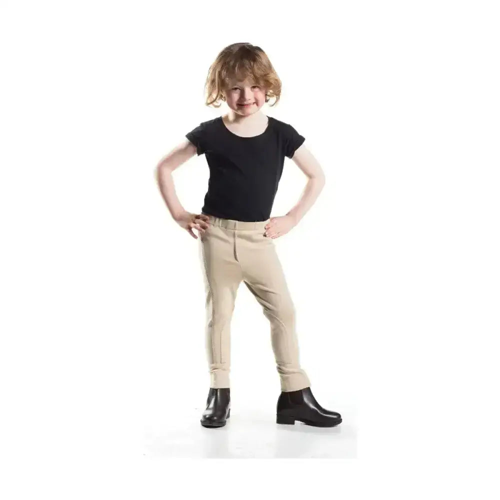 A child wearing beige pull-on tots jodhpur pants with a black top and boots in equestrian zeddy tots style