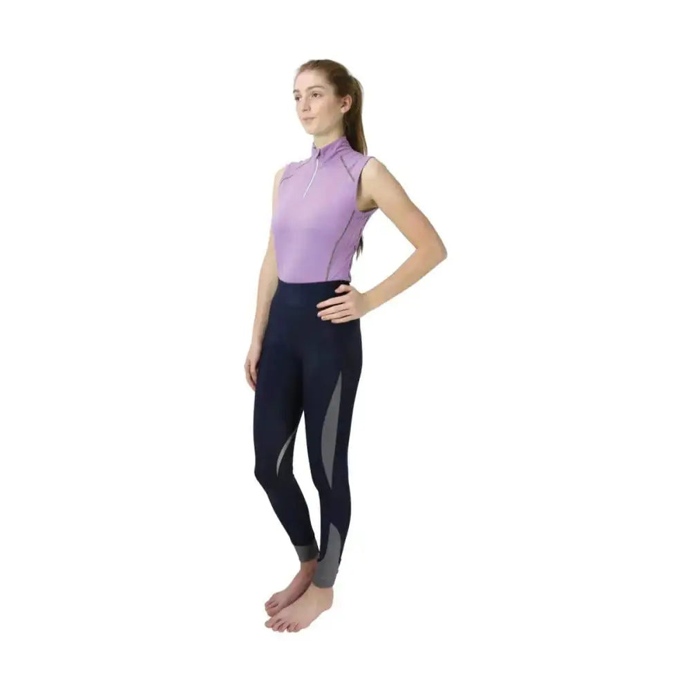 A woman wearing a lavender hy sport active sleeveless top with high collar and navy base layers leggings