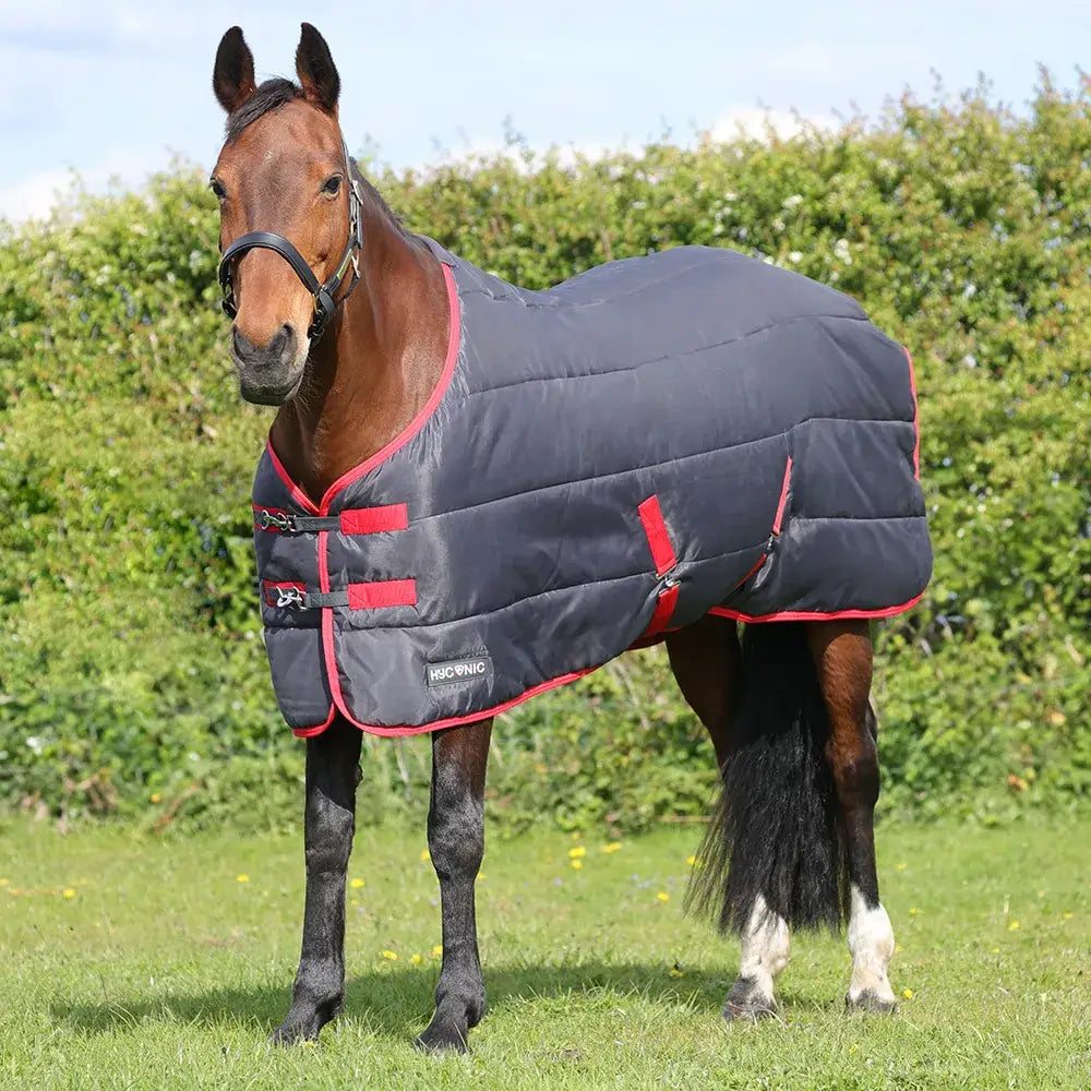 Dark gray quilted hyconic 100g stable rug with red trim black buckles and branded label designed for horses