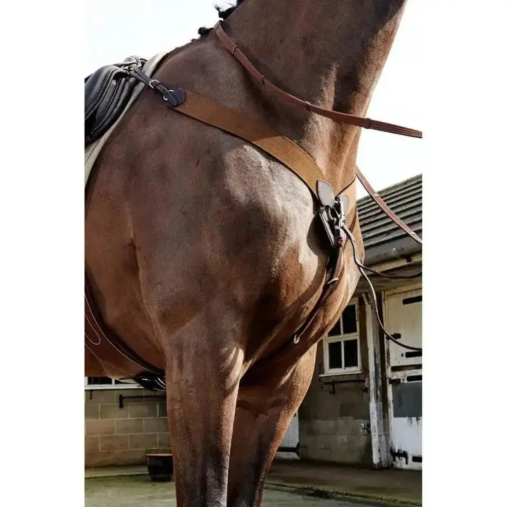 Brown leather horse saddle with black padding and metal hardware featuring the john whitaker ready ride elastic breastplate