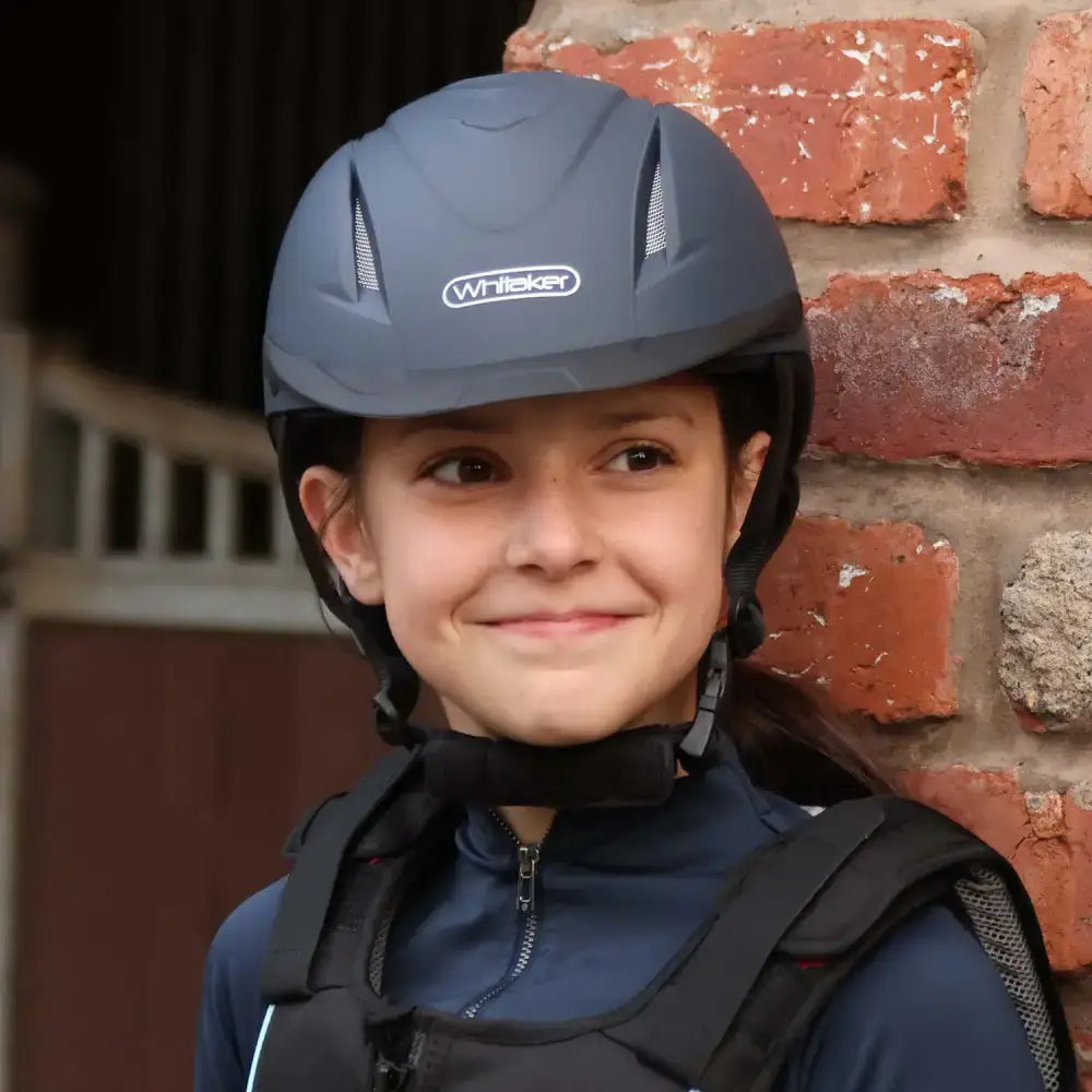 Dark gray john whitaker nrg riding helmet rh040 adjustable with ventilation slots and black chin strap for young riders