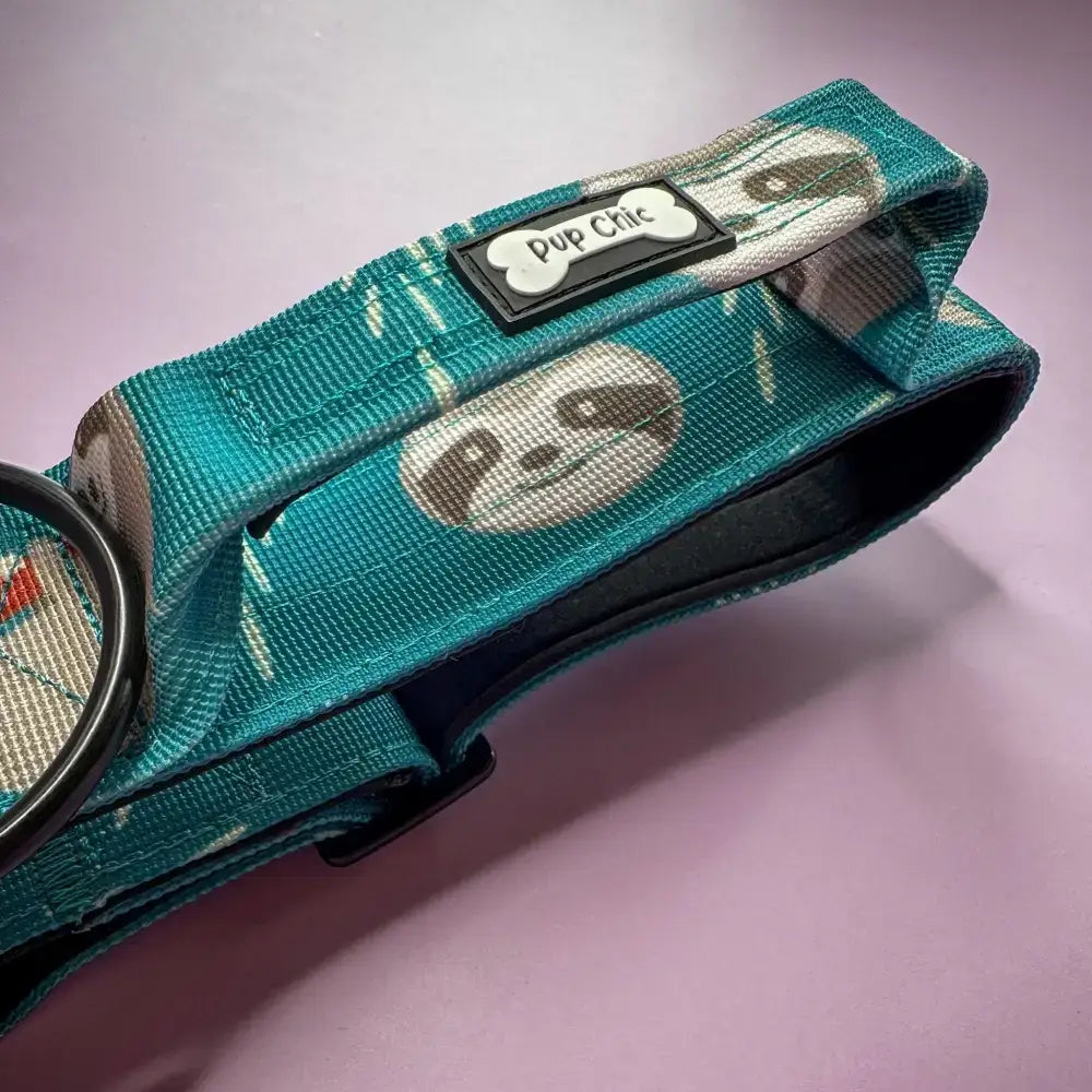 Teal fabric tactical dog collar with playful panda lazy sloth print and black pup chic bone tag on mint green base