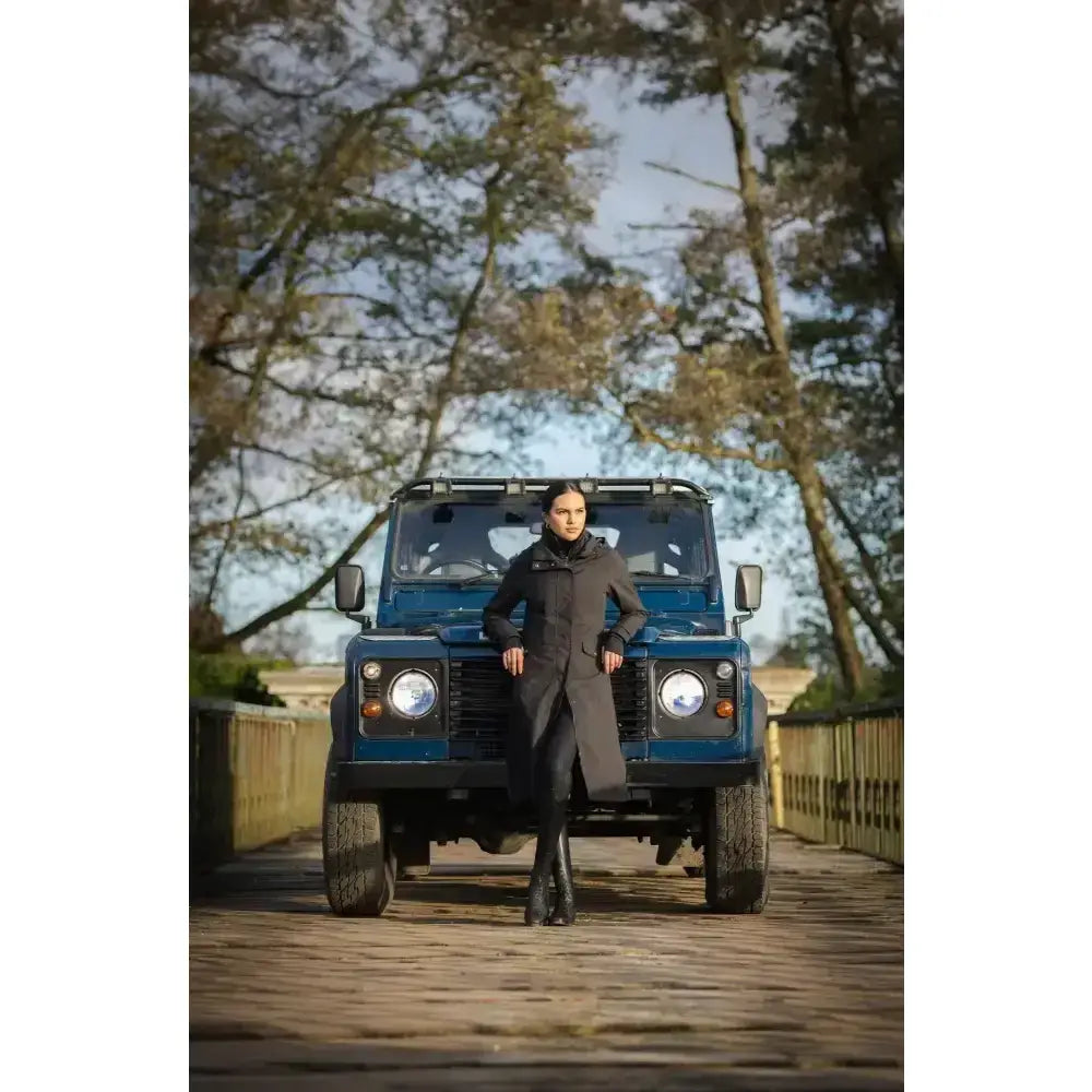 Blue land rover defender suv next to lemieux amelie waterproof lightweight black riding coat for outdoor use