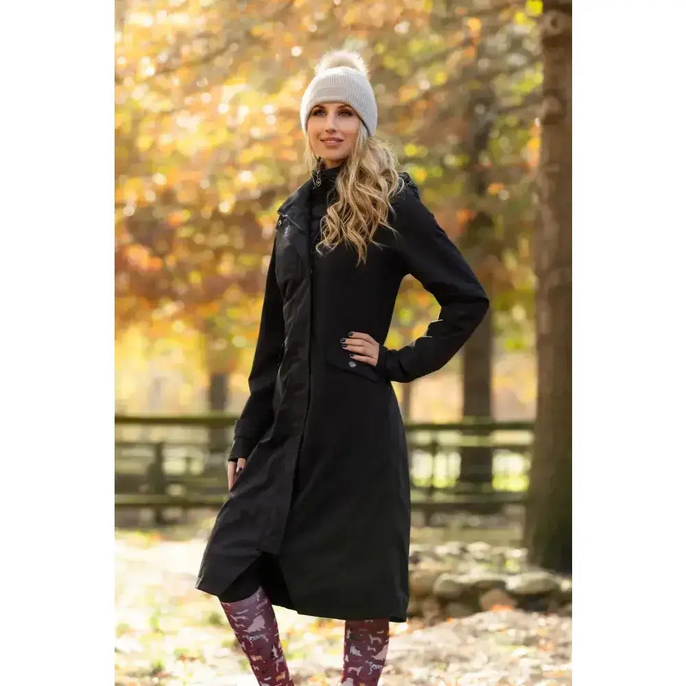 Black lemieux amelie waterproof lightweight riding coat with high collar and front zipper worn over patterned leggings