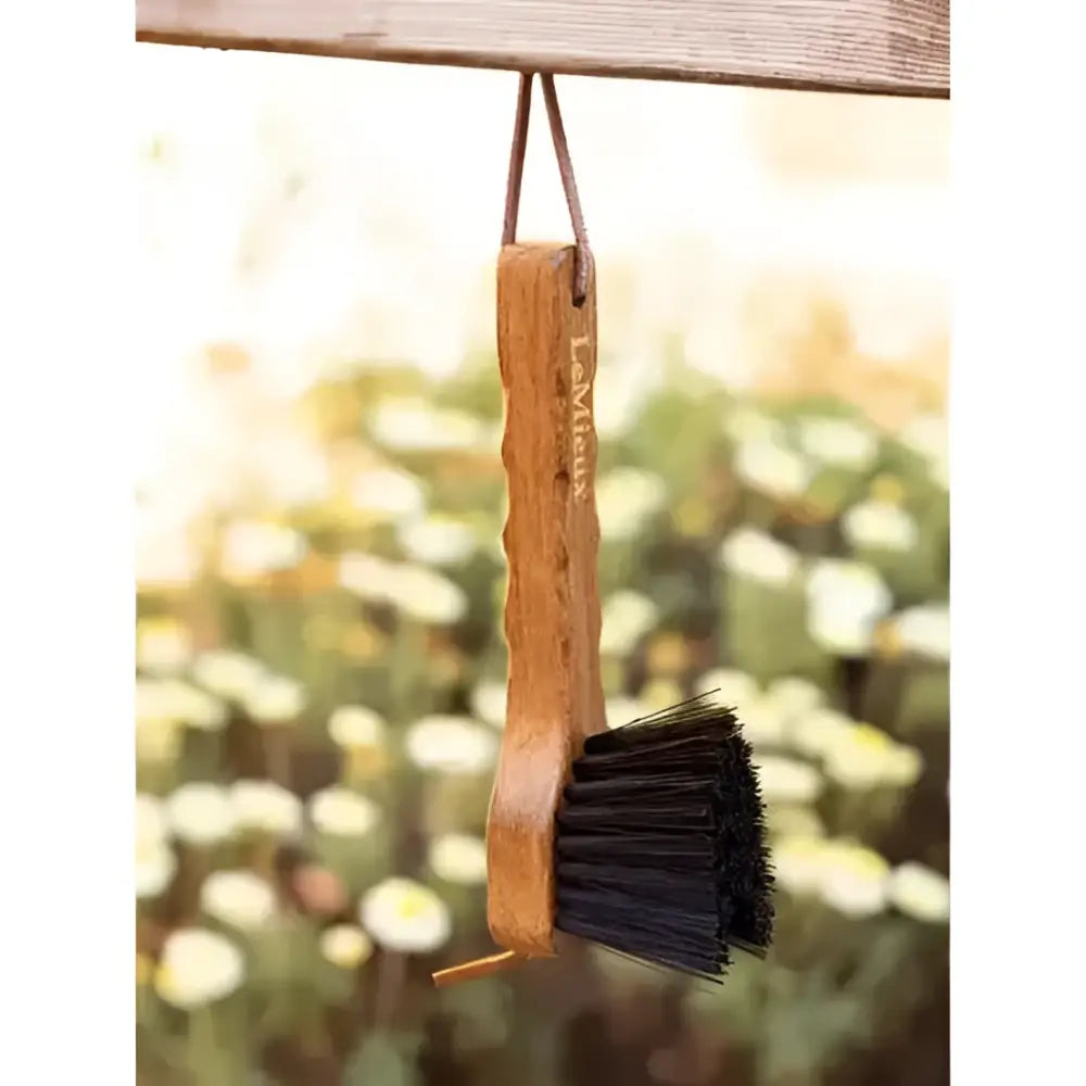 A lemieux artisan hoof pick with a wooden handle and black bristles for removing packed mud easily