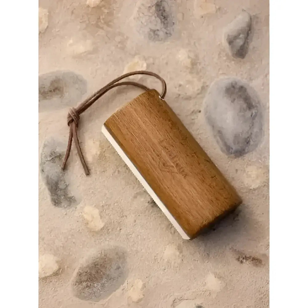 A lemieux artisan shedding comb featuring a rectangular wooden file with a white abrasive side and braided leather cord in brown