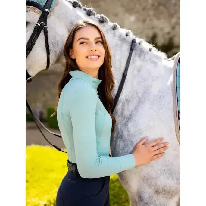 A light blue long sleeved lemieux base layer aqua with high collar and subtle seam detailing for riding comfort