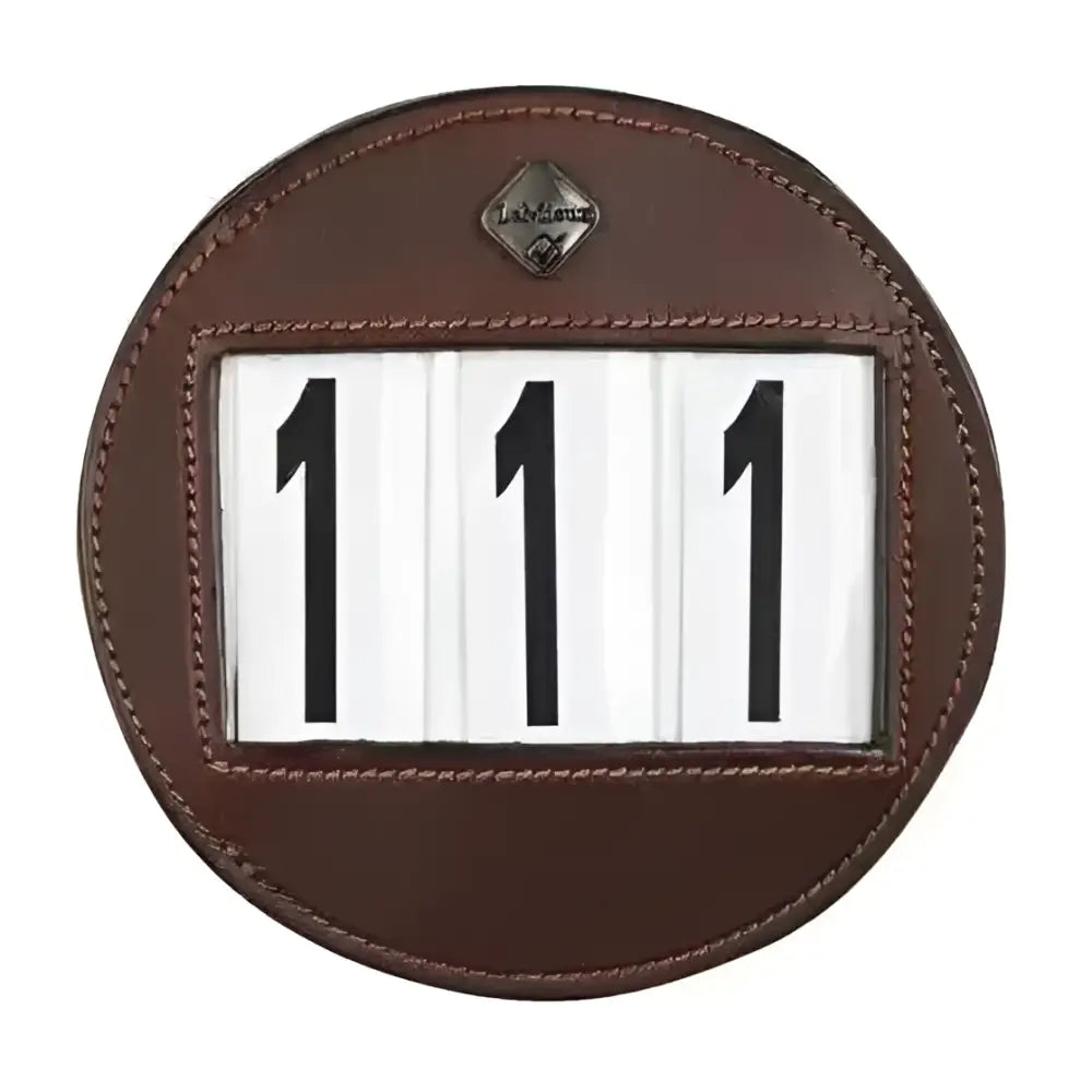 Brown leather bridle number holder showing 111 with black numerals and metallic emblem lemieux bridle number