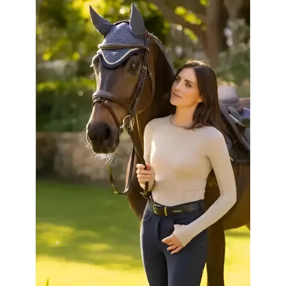 The lemieux britney seamless long sleeve almond top is shown with a horse wearing a dark blue textured bridle and ear covers