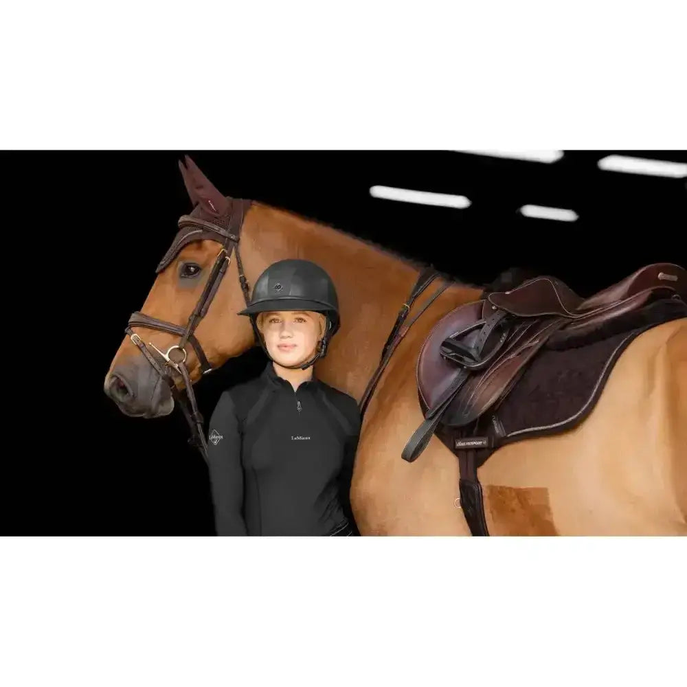 Black equestrian helmet with a glossy finish and subtle branding paired with lemieux crystal suede close square brown saddle