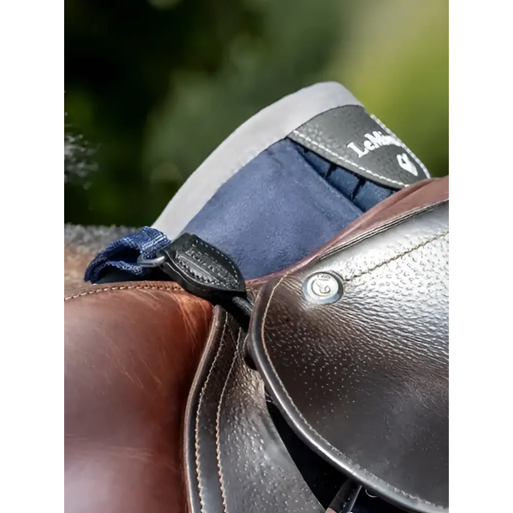 Brown leather saddle with navy blue padded flap and black stitching showing lemieux d-ring extender for adding extra room