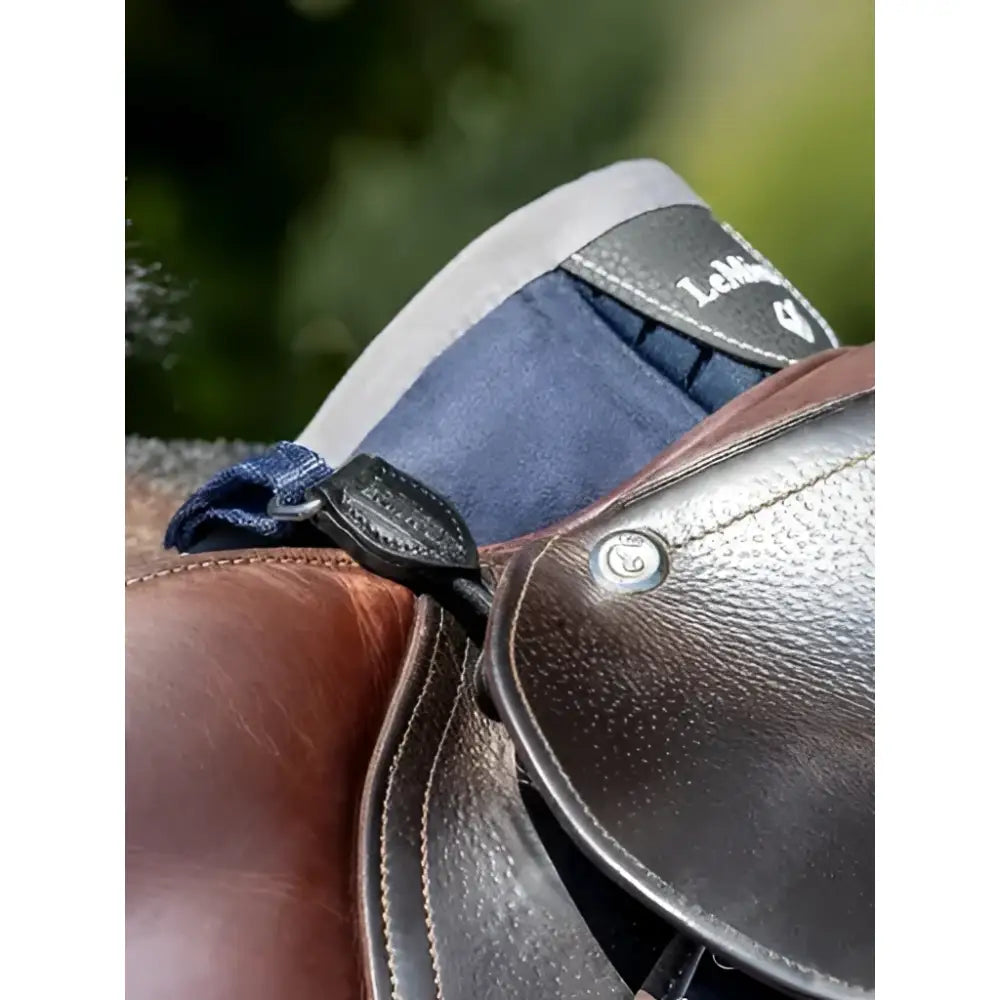 Brown leather saddle with navy blue padded flap and black stitching showing lemieux d-ring extender for adding extra room