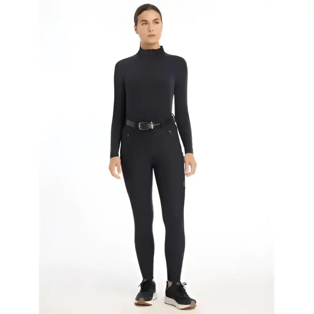 Black lemieux drytex waterproof breeches knee grip navy with high neck long sleeves and subtle side pockets paired with black shoes