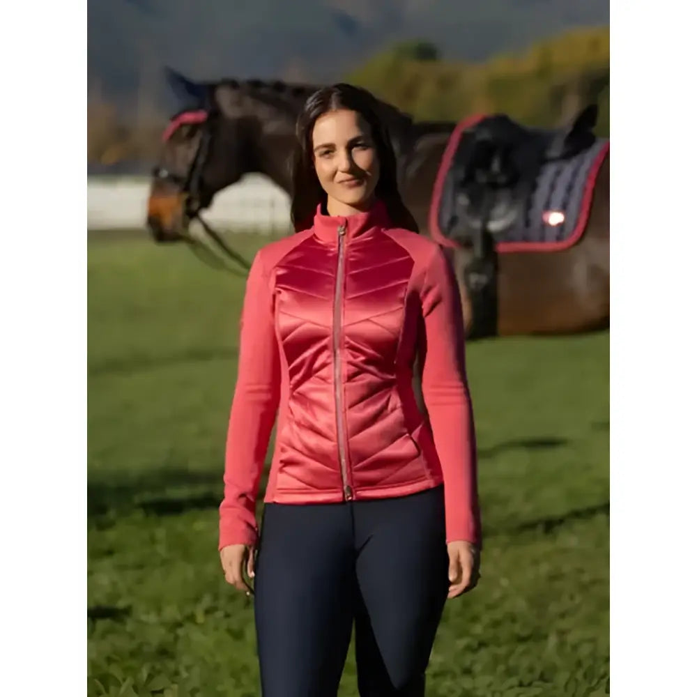 A woman wearing a vibrant coral lemieux dynamique jacket cranberry with quilted zip-up design and high collar
